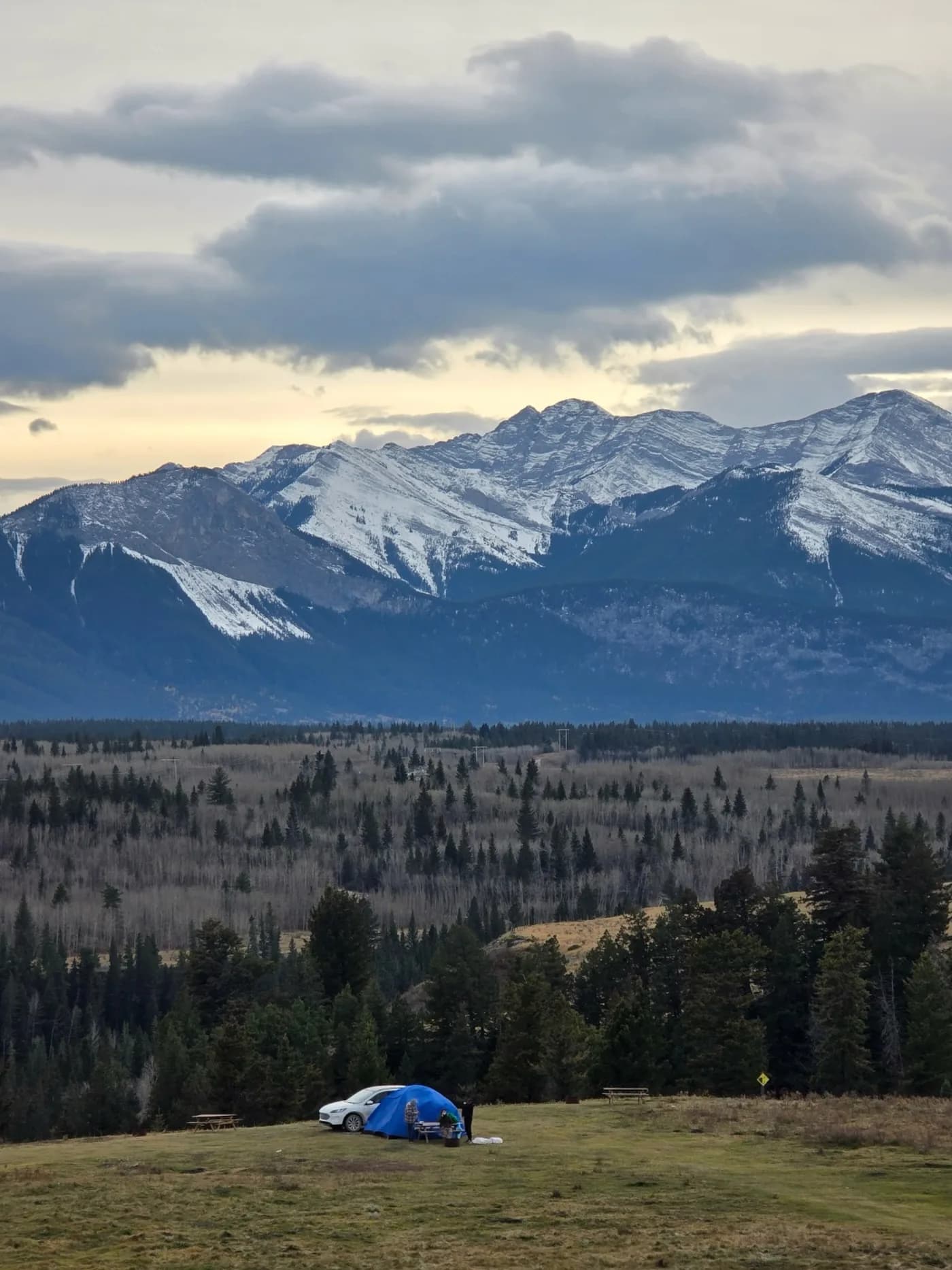 Tent beneath snowy mountain peaks at dusk